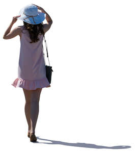 backlit woman in a pink summer dress walking