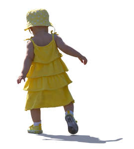 backlit baby girl in a yellow dress walking