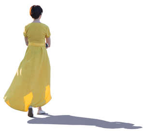 backlit woman in a long yellow dress walking