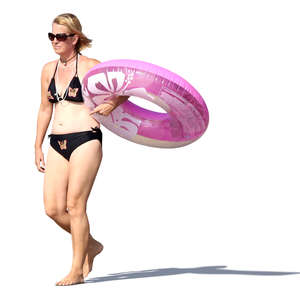 woman walking on the beach and carrying a floatie