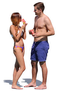 couple standing on the beach and eating watermelon