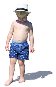 little boy with a hat standing on the beach