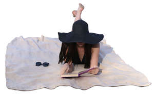 woman with a black hat reading a book on the beach