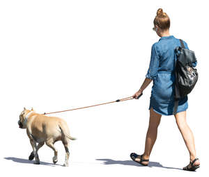 woman in a denim dress walking a dog