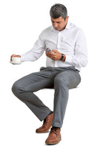 man in a suit sitting in a cafe and drinking coffee