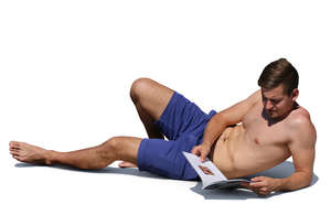 man lying on the beach and reading a magazine