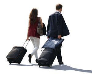 backlit man and woman pulling big suitcases