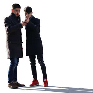 two backlit asian men standing and looking at a phone
