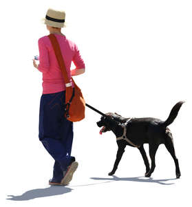 backlit woman walking with a black dog