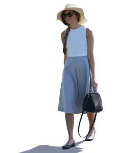 backlit woman with a summer hat walking