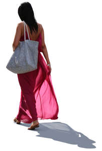 backlit woman in a long pink summer dress walking