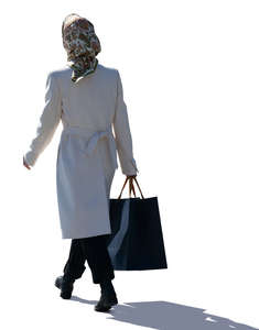 backlit woman with a headscarf walking