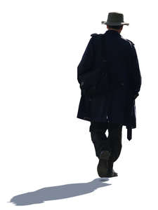 backlit man with a coat and hat walking