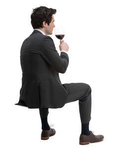 man in a suit sitting and drinking wine