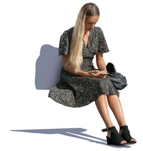 woman in a summer dress sitting and looking at her phone