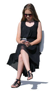 girl in a black dress sitting and looking at her phone