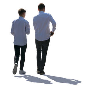 two backlit teenage boys walking