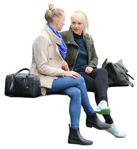 two women sitting on a bench and talking