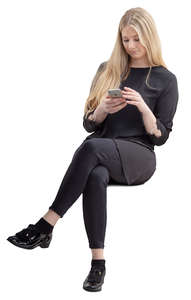 woman in black sitting and looking at her phone