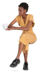 black woman in a yellow jumpsuit sitting in a cafe