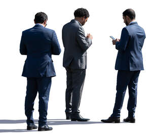 three businessmen standing and checking their phones