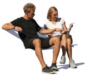 man and woman sitting on a bench and reading a magazine