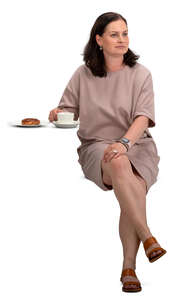 woman in a beige dress sitting in a cafe