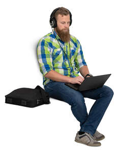 man with headphones sitting and working with laptop