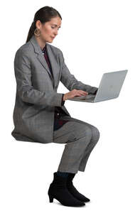 woman in a grey costume sitting and working with laptop