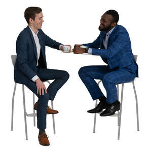 two men in suits sitting in a cafe and talking