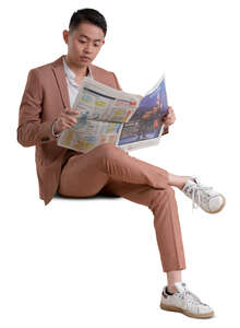 asian man in a pink suit sitting and reading a newspaper