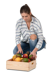 woman squatting and putting fruits in a box