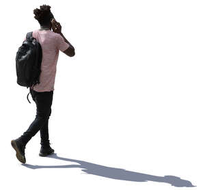 backlit man walking and talking on a phone