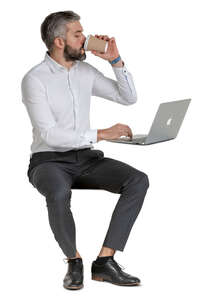 man sitting at an office desk and drinking coffee