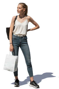 young woman with a shopping bag standing outside in the sun