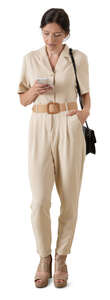 cut out woman in a beige jumpsuit standing and checking her phone