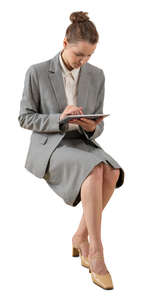cut out young businesswoman sitting and looking at her tablet