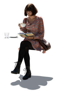 cut out young woman sitting in a cafe and readin a book