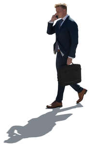 cut out backlit businessman walking and talking on a phone