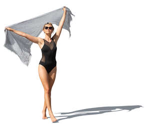 cut out woman in a black swimsuit holding a light towel walking on the beach