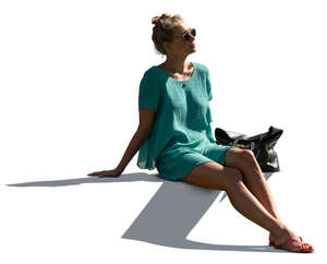 cut out sidelit woman in a green summer dress sitting