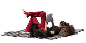 cut out young woman lying on the picnic blanket and reading a book