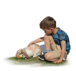 cut out boy sitting on the grass and petting a rabbit