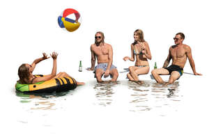 cut out group of young people sitting by the pool and drinking and playing with a beach ball