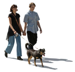 cut out young backlit couple with a dog walking hand in hand