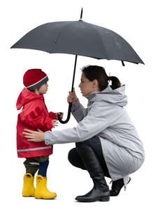 cut out mother squatting and talking to her little son in the rain
