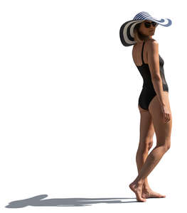 sidelit woman in a swimsuit and wearing a big summer hat standing