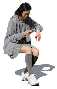 cut out woman sitting at a table and looking at her phone