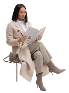 cut out woman in a long beige overcoat sitting and reading