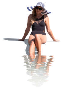 cut out woman sitting at the edge of the pool with her legs in the water